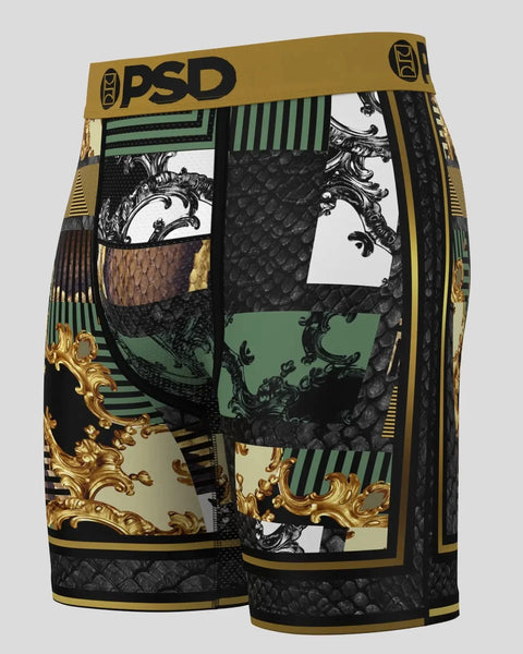 PSD shorts with gold waistband featuring black serpent scale texture, ornate scrollwork, green striped panels, and mixed patt