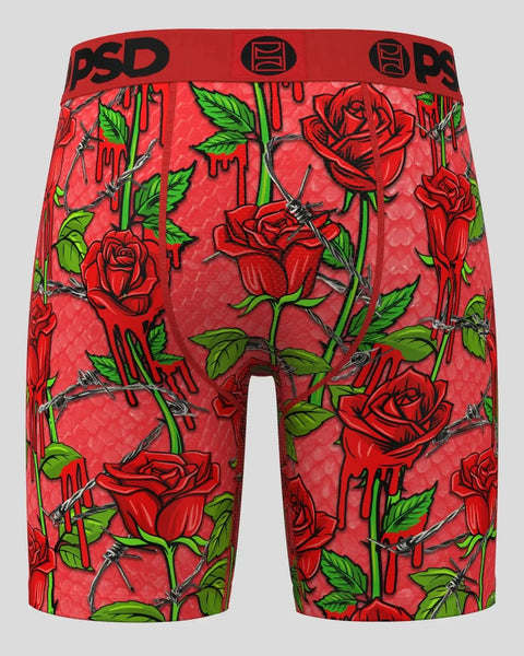 Red shorts with all-over red rose, green leaf, and thorn print, black waistband with PSD branding.