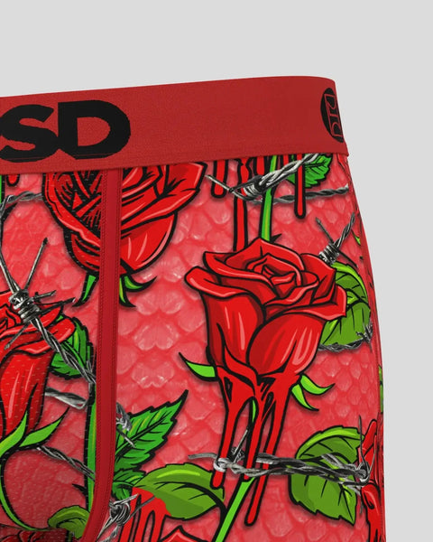 Red boxer briefs with illustrated roses, black thorns, green leaves, and brand waistband on coral background.
