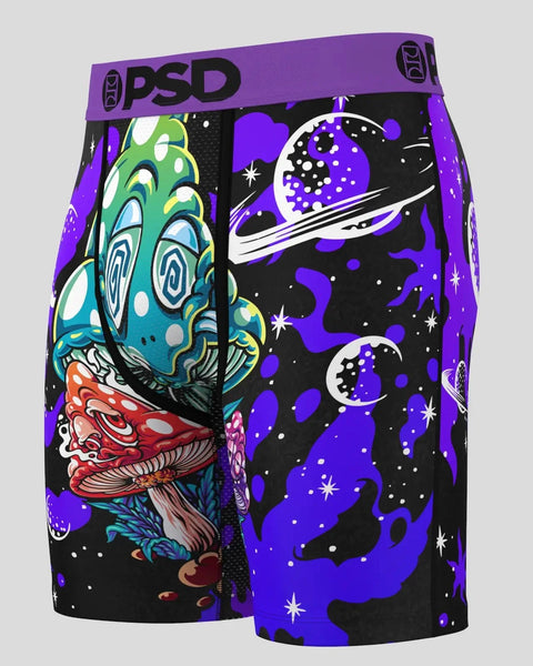 PSD brand shorts with purple waistband featuring colorful mushroom and space-themed graphics on black fabric.