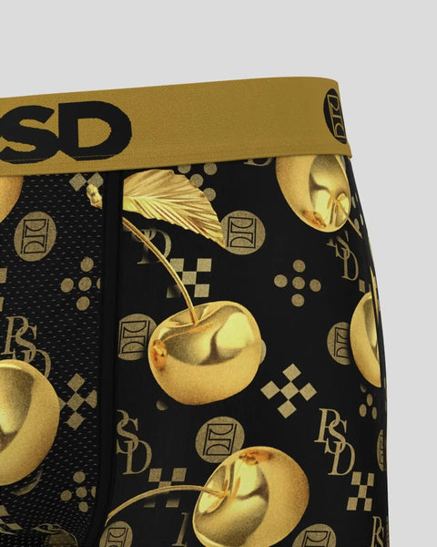Gold and black patterned fabric with golden cherries, stems, geometric shapes, and brand logo on elastic waistband.