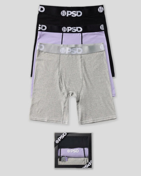 Three-pack PSD boxer briefs in black, lavender, and gray with branded elastic waistbands, displayed flat and in packaging.