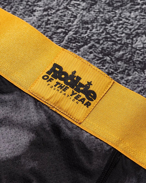 Yellow fabric band with black woven label featuring duck silhouette and text on gray textured garment.