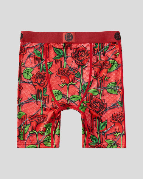 Red boxer briefs with all-over rose and thorny stem print in green and black on quilted fabric.