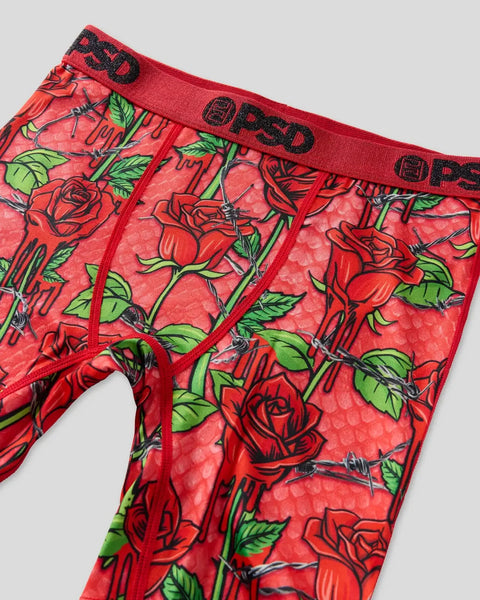 Red boxer briefs with red roses, green leaves, and black thorns print, black waistband with text.