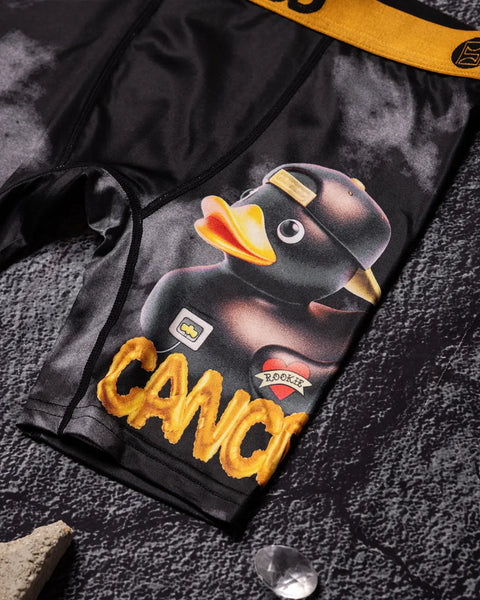 Black shorts with graphic print of cartoon duck with yellow beak and gold text reading 
