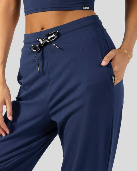 Navy blue joggers with drawstring waistband, side pockets, and tapered legs on model.