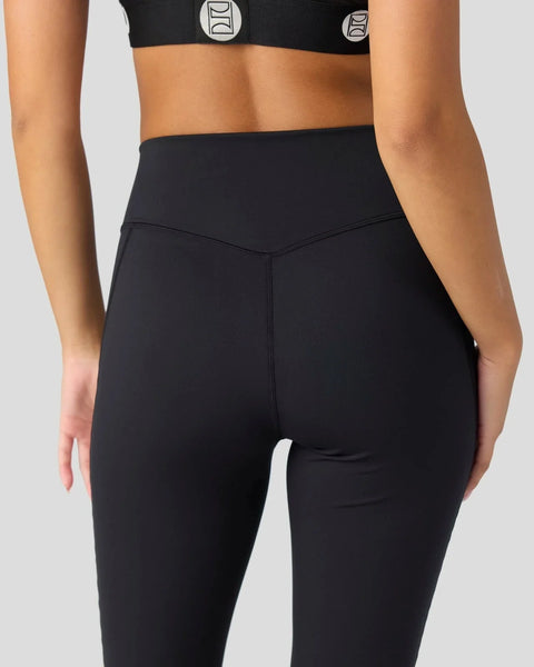 Black high-waisted leggings with white side stripe and matching black sports bra with logo detail.