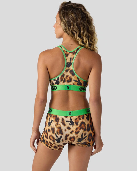 Woman wearing leopard print sports bra and shorts set with green trim and black Playboy bunny logo repeated throughout.