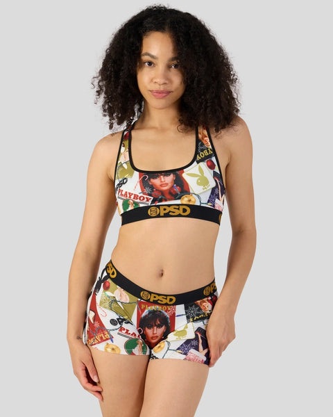 Woman wearing a Playboy-branded two-piece set with colorful vintage magazine cover graphics and black PSD waistbands.