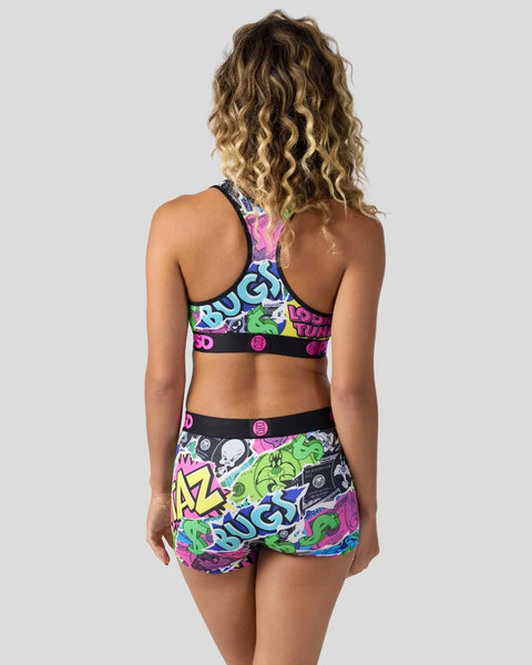 Woman wearing colorful Looney Tunes-themed sports bra and shorts with neon graffiti-style graphics and black trim.