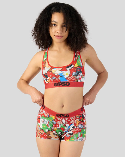Woman wearing red Looney Tunes holiday-themed sports bra and shorts with cartoon characters and PSD branding.