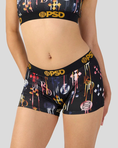 Black PSD boxer shorts with yellow logo band and multicolored geometric and abstract print pattern.
