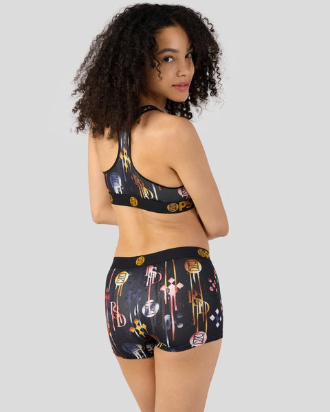 Black sports bra and shorts set with gold and red metallic geometric patterns and branding.