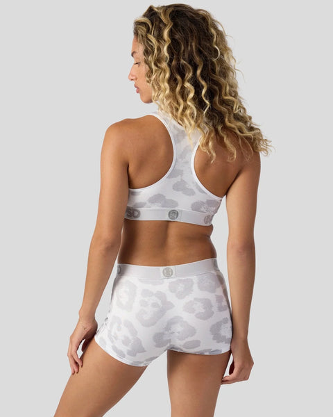 Woman wearing white sports bra and shorts with gray leopard print pattern, shown from back view.