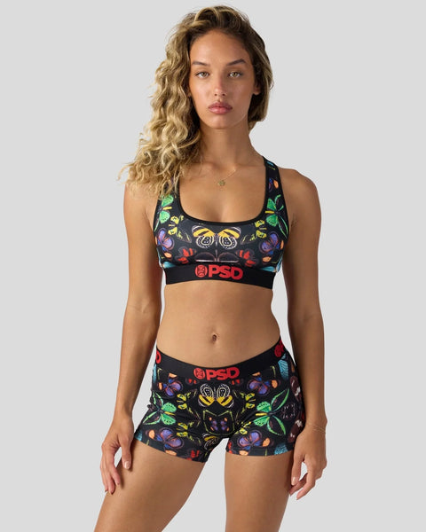 Black sports bra and shorts set with colorful butterfly and floral print, red PSD branding on elastic waistband.
