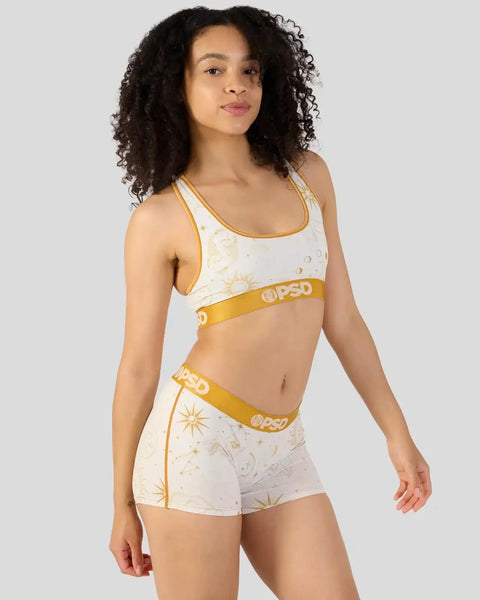 Woman wearing white and gold two-piece set with celestial sun and star print and yellow PSD waistband.