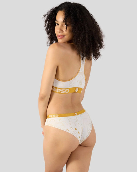 Woman wearing white sports bra and brief set with gold zodiac symbol print and yellow waistbands.