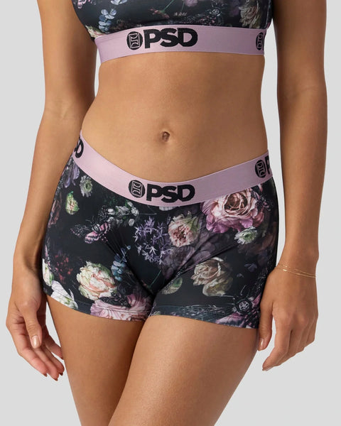 Woman wearing dark floral PSD sports bra and matching boy shorts with pink waistband.
