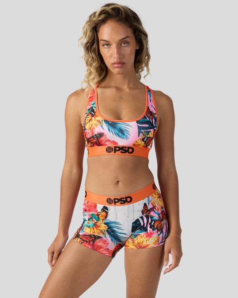 Woman wearing colorful tropical floral sports bra and shorts set with orange PSD waistbands.