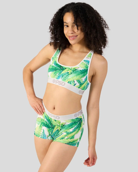 Woman wearing green leaf-print sports bra and matching shorts with white elastic bands.