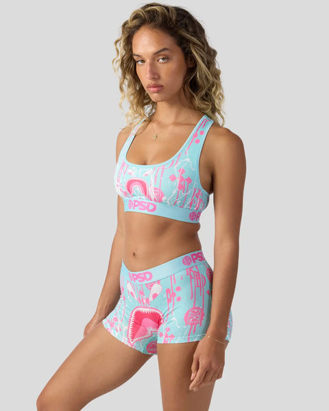 Woman wearing turquoise and pink patterned sports bra and matching shorts with geometric design.