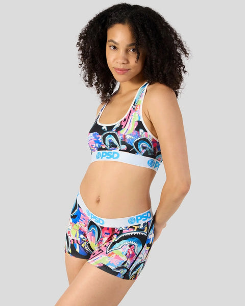 Woman wearing colorful shark-print sports bra and shorts set with blue waistbands.