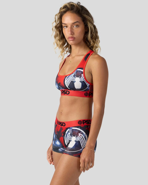 Woman wearing red and navy sports bra and shorts set with white Venom spider emblem graphic and red waistband.