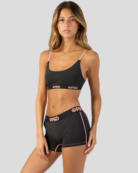 Black sports bra and shorts set with pink straps and waistband trim featuring logo branding.