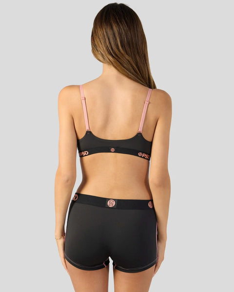 Black sports bra with pink straps and matching black shorts with decorative circular embellishments.