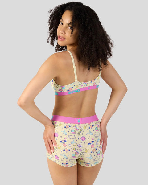Woman wearing yellow modal bra and shorts set with colorful space-themed print and pink elastic bands.