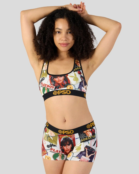 Woman wearing Playboy-branded sports bra and shorts with vintage magazine cover print and black elastic waistbands.
