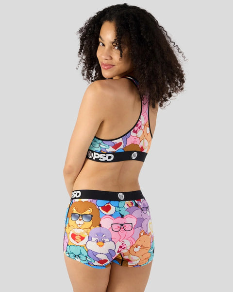Colorful Care Bears print sports bra and shorts set with black PSD waistbands and character graphics.