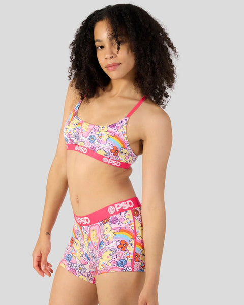 Person wearing Care Bears-patterned sports bra and boy shorts with pink trim and PSD branding.