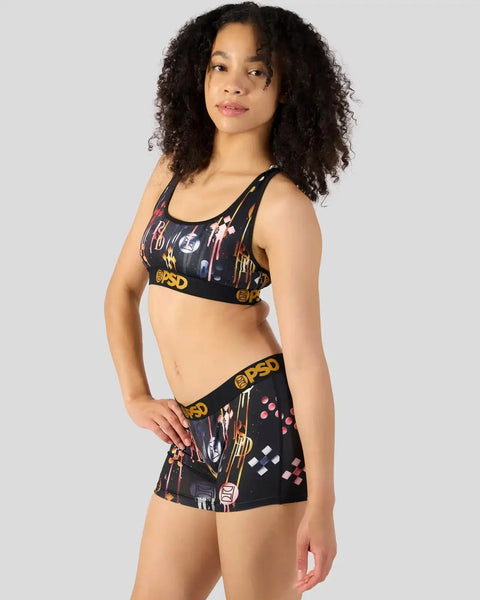 Black sports bra and shorts set with colorful graphic print and gold trim details.