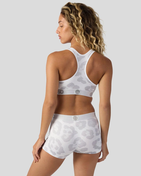 Woman wearing white sports bra and shorts with gray leopard print pattern, shown from back.