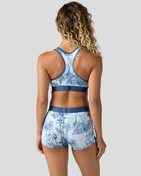 Woman wearing blue and white floral sports bra and matching shorts, shown from behind.