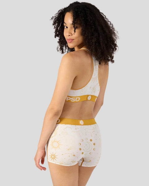 White and gold celestial-print sports bra and shorts set with gold elastic waistbands, shown on model from back.