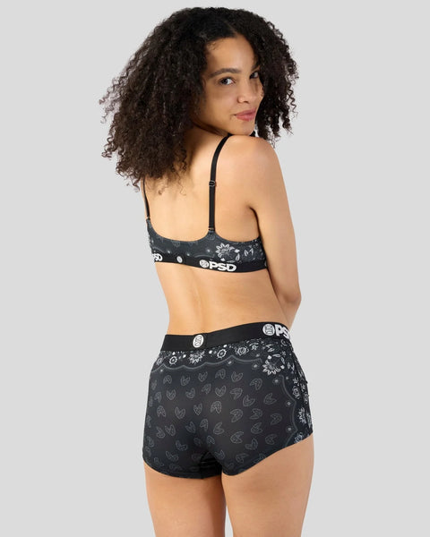 Black bandana-print bra and shorts set with PSD branding, shown from back view on model with curly hair.