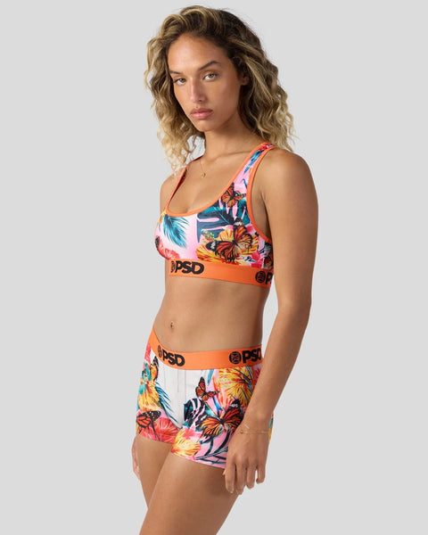 Woman wearing colorful tropical floral print sports bra and matching shorts with orange elastic waistband.