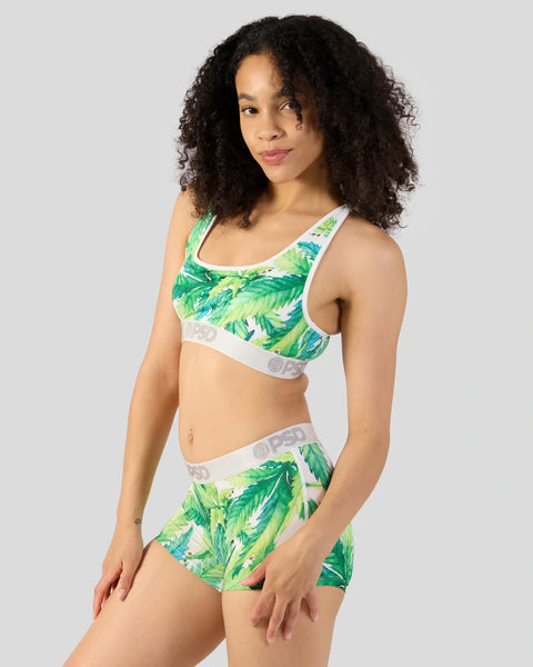 Woman wearing green leaf-print sports bra and matching shorts with white elastic waistband.