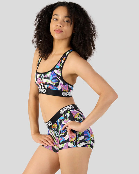 Woman wearing PSD sports bra and boxer shorts with colorful mushroom print on black background.