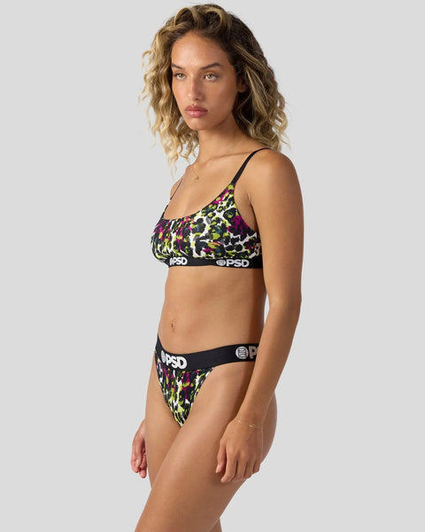 Woman wearing a two-piece swimsuit with multicolored leopard print pattern and black trim with branding.