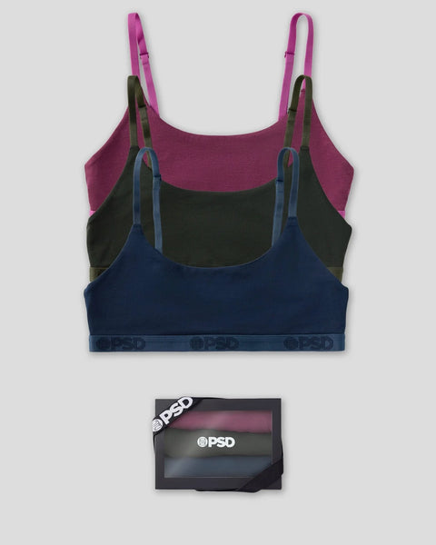 Three wireless bras in magenta, black, and navy blue with matching straps and branded waistband displayed with packaging.