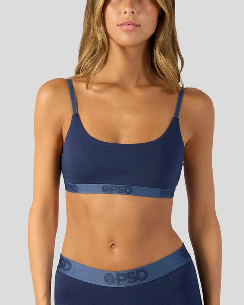 Woman wearing navy modal bra with thin straps and branded elastic band at waistline.