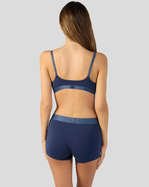 Woman wearing a navy modal bra and shorts set with contrasting waistband, shown from behind.
