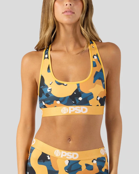 Woman wearing yellow and navy abstract camo sports bra with PSD branded elastic band and matching waistband.