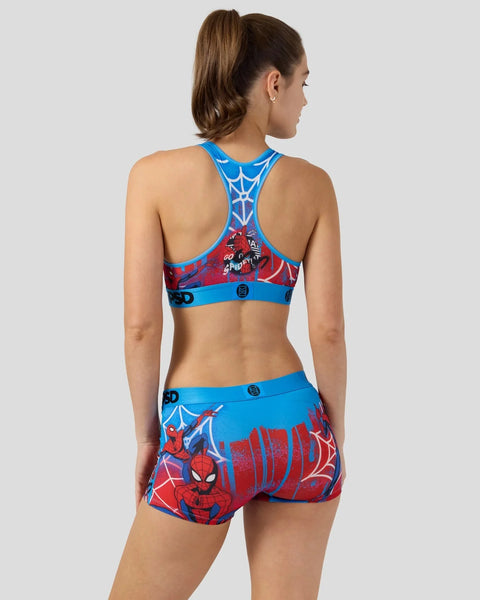 Woman wearing blue and red Spider-Man sports bra and shorts with web and character graphics.