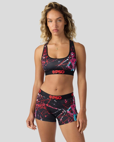 Woman wearing black sports bra and shorts with red and blue spider web graphic print and PSD branding.