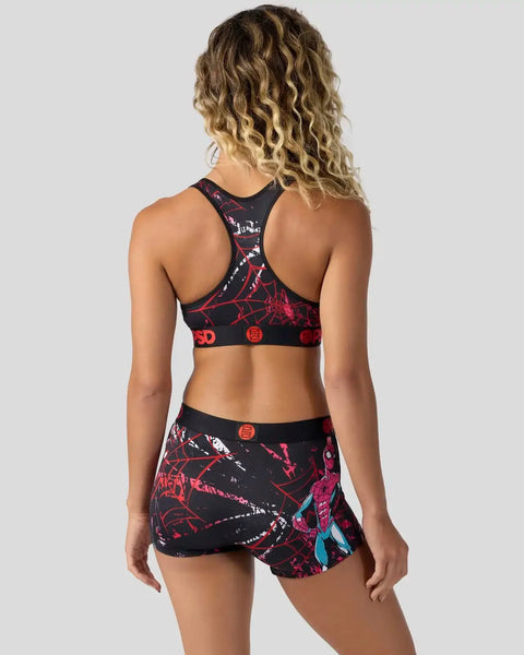Black and red spider web patterned sports bra and matching skirt set shown from back view on model.